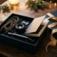 Coffret cadeau ouvert sur une table en bois : une sangle d'appareil photo, un objectif, un mini-trépied et un livre photo, à côté d'un paquet au ruban doré et de lumières de Noël